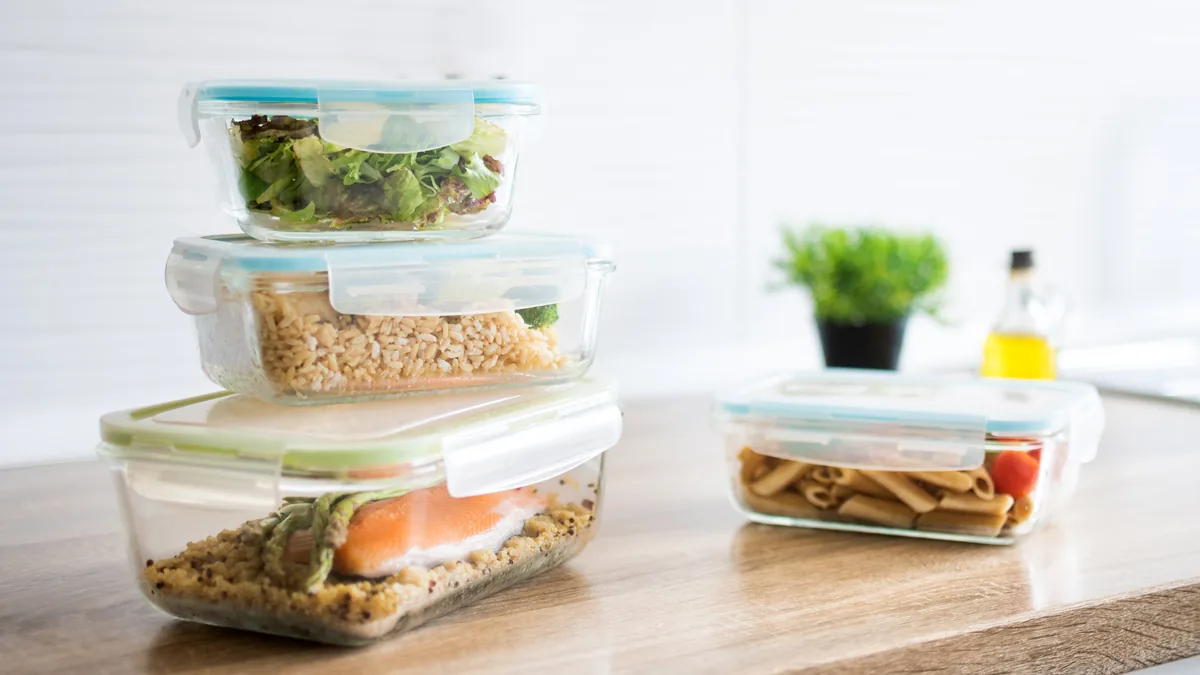 Meal-prep containers of salmon, rice, salad and pasta