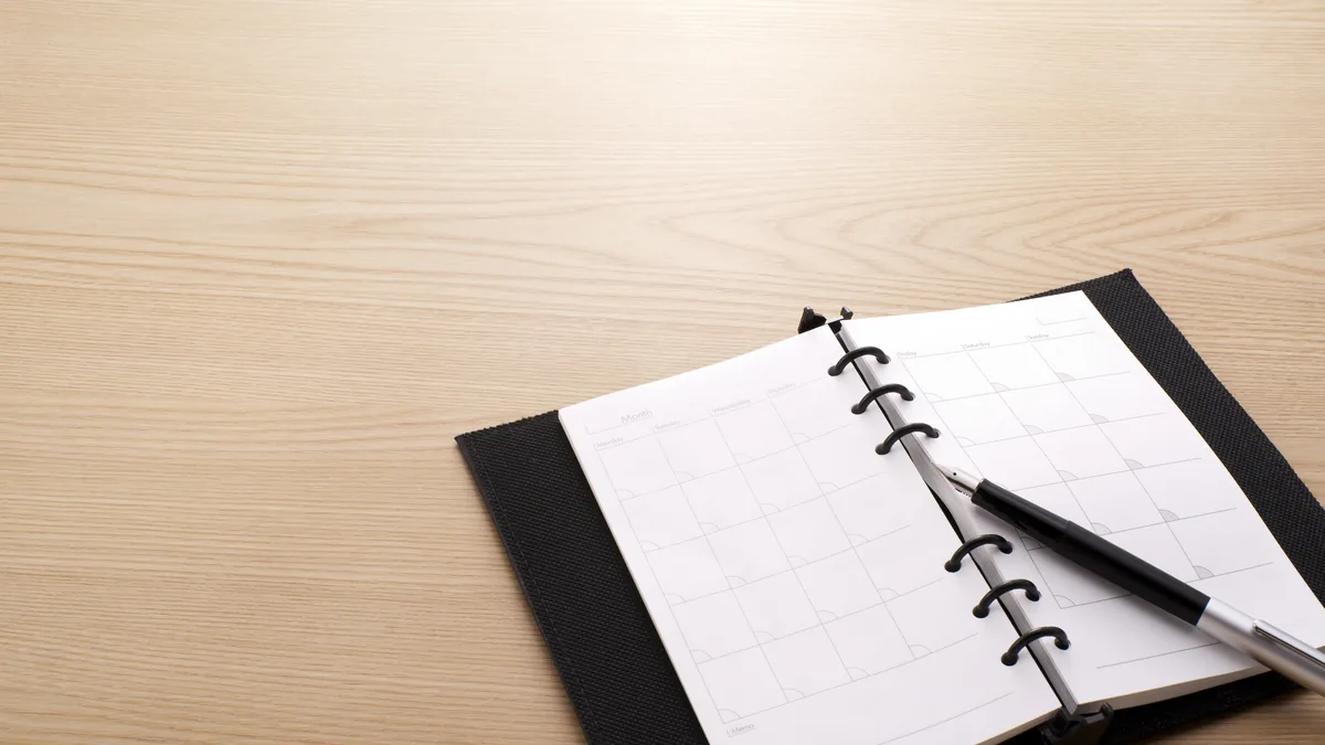 An open planner and pen on a desk